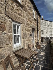 eine Holzbank vor einem Steingebäude in der Unterkunft New renovated beach front cottage in Mousehole