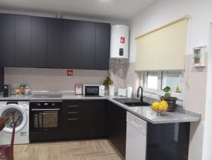 a kitchen with black cabinets and a sink and a dishwasher at Casa Pito in Santo António do Baldio