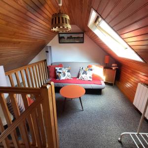 a attic room with a couch and a table at "La maison d'étape" proche de la Riviera Bretonne in Saint-Évarzec