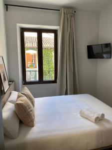 a bedroom with a large white bed with a window at Casa Azhuma in Granada