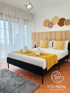a bedroom with a large bed with yellow and white pillows at Vila Maria Beach Apartments in Pataias