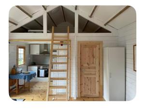 a room with a loft bed with a ladder and a kitchen at Sportfiskestugan in Färjestaden