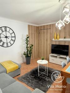 a living room with a large clock on the wall at Vila Maria Beach Apartments in Pataias