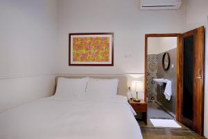 a bedroom with a white bed and a painting on the wall at Entire Heritage Villa Family friendly in the Center of Yogya with Swimming Pool - Up to 9 people in Yogyakarta +19 photos