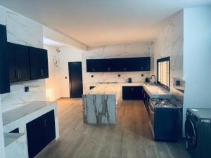 eine große Küche mit schwarzen und weißen Arbeitsplatten in der Unterkunft Appartement 2 chambres- salon- Cuisine Résidence Aramys Ngaparou in Ngaparou