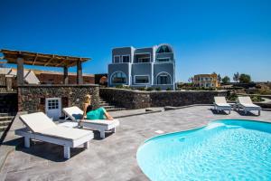 a woman laying on a chair next to a swimming pool at Our Villa Santorini in Akrotiri