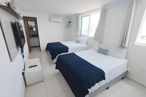 ein Hotelzimmer mit zwei Betten und einem Fernseher in der Unterkunft Caribbean Blue - Jardim Oceania in João Pessoa + 56 Fotos