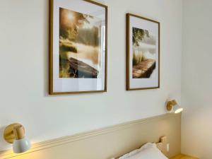 two framed pictures on a wall above a bed at La Rose des Marais - Renovated & Fully Equipped House in Houesville