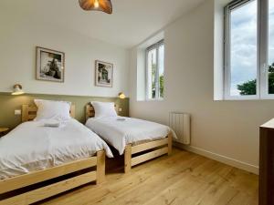 two beds in a room with two windows at La Rose des Marais - Renovated & Fully Equipped House in Houesville