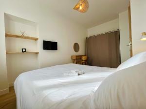 a bedroom with a white bed and a tv at La Rose des Marais - Renovated & Fully Equipped House in Houesville +14 photos