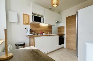 a small kitchen with white cabinets and a microwave at La Rose des Marais - Renovated & Fully Equipped House in Houesville