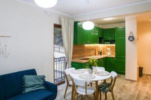 a kitchen with green cabinets and a white table and chairs at Adria Mare one bedroom apartment in Tušupi