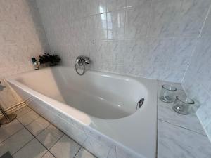 La salle de bains est pourvue d'une baignoire blanche et de carrelage blanc. dans l'établissement Eickhof Ferienhaus 200qm - Ferienhof Günter - bis 8 Personen - familienfreundlich, à Warnow 26 autres photos