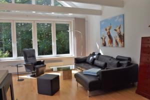 a living room with a black leather couch and chairs at Ferienhaus Blaues Haus Ockholm in Ockholm