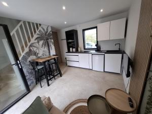 Una cocina con gabinetes blancos y una mesa y sillas. en Ty C&K Breizh, en Plerguer