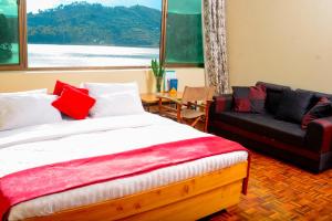 um quarto com uma cama, um sofá e uma mesa em Bunyonyi Safaris Resort em Kabale
