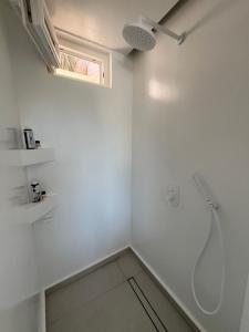 a white bathroom with a shower and a window at Neso seafront studio Paros in Parasporos