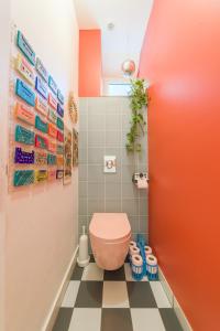 a bathroom with a pink toilet on a checkered floor at Les Seventies - Confort Vintage proche gare in Chambéry +19 photos