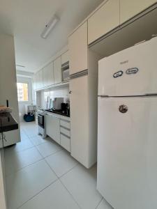 a white kitchen with a refrigerator and a stove at Aruana - Diamante in Aracaju