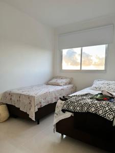 two beds in a white room with a window at Aruana - Diamante in Aracaju