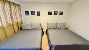 two beds in a room with pictures on the wall at Casa Mia Nanacamilpa Luciernagas in Nanacamilpa