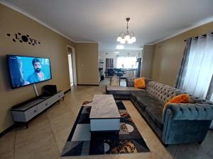 a living room with a couch and a flat screen tv at Ivy Cottage in Harare