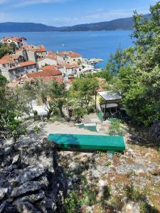 a green bench sitting on top of a rocky hill at Apartments and rooms Roberto B. in Valun