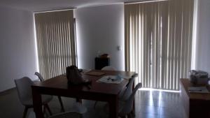 a dining room with a table and chairs and a large window at Departamento céntrico amplio in Río Cuarto