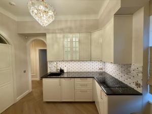 a kitchen with white cabinets and a chandelier at KR Apartment Kaunas in Kaunas