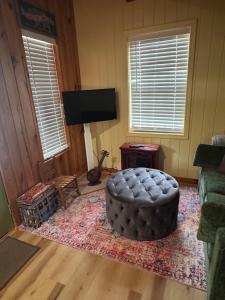 a living room with a ottoman and a television at 109 Vinewood Cabin-1 Bedroom in Brewton