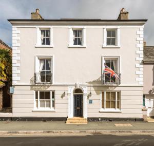 een wit huis met een Britse vlag op een balkon bij Ashburton Court Guest House in Ashburton