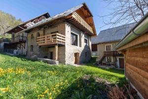 ein altes Steinhaus mit einem Holzdach in der Unterkunft Cabana & La Grange aux 7 Marmottes in Saint-Alban-des-Villards