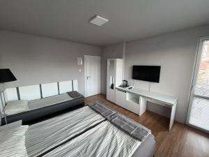 a bedroom with two beds and a desk and a television at Стаи за гости Villy in Kazanlŭk