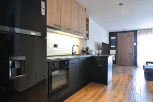 una cocina con electrodomésticos negros y armarios de madera en Felina Apartments, en Leptokarya