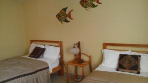 ein Schlafzimmer mit 2 Betten und einem Tisch mit einer Lampe in der Unterkunft Hostal Doña Maria in Pedasí Town