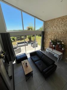 a living room with a black couch and a large window at Détente et Spa au cœur des vignes ! in Moulis-en-Médoc