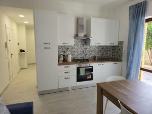 a kitchen with white cabinets and a wooden table at Il MaRe dei delfini in Ladispoli