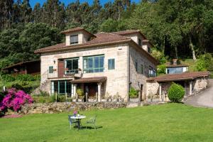 a large stone house with a table in the yard at 3 Cabras Perdidas in Arbo