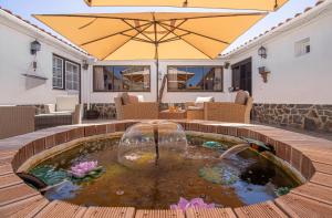 a patio with a pond with an umbrella at Quinta Penedo das Antas - AL in Sertã