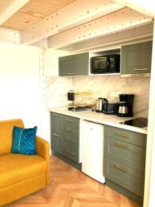 Una cocina con gabinetes verdes y un sofá naranja. en Studio de Rêve à Versailles Plein Centre , 500m Château, 350m Gare Rive Gauche, en Versalles