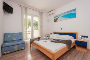 a bedroom with a bed and a blue chair at House Mimica in Stanići +49 photos