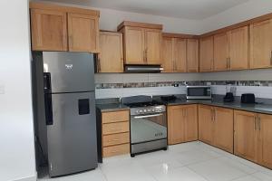 a kitchen with wooden cabinets and a stainless steel refrigerator at Casa cerca del aeropuerto. in Monte Llano +2 photos