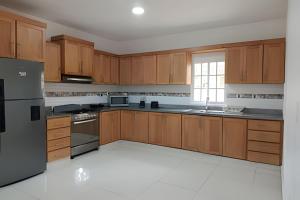 a kitchen with wooden cabinets and stainless steel appliances at Casa cerca del aeropuerto. in Monte Llano