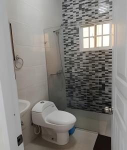 a white bathroom with a toilet and a window at Casa cerca del aeropuerto. in Monte Llano