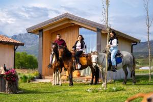 three people riding horses in front of a cabin at Fishta Guesthouse - Mrizi i Zanave in Fishtë