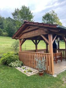 a wooden gazebo with a bench in a field at Chalupa na Pasekách in Valašská Bystřice +17 photos