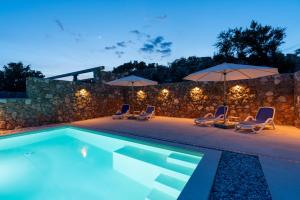 a swimming pool with lounge chairs and umbrellas at Ferienhaus Sana in Klenovica