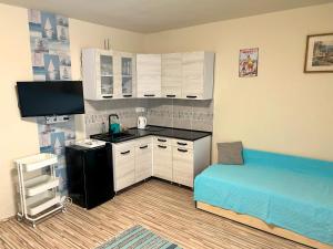 a small kitchen with white cabinets and a blue bed at Nosztalgia Balaton Apartmanház in Vonyarcvashegy