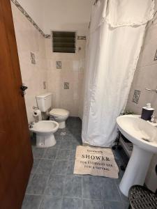 a bathroom with a sink and a toilet and a shower curtain at VIA VALENTINA "el deseo de volver" departamentos temporales sobre Av Eden centro in La Falda
