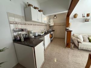a small kitchen with white cabinets and a couch at VIA VALENTINA "el deseo de volver" departamentos temporales sobre Av Eden centro in La Falda +11 photos